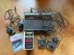 Atari 2600 Video Computer System W/ Four Controllers, Nine Games, And More. Fixed Price $99.00.